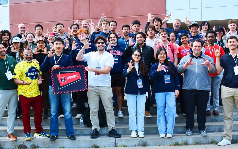 A large group of students celebrating together on the steps outside a regional MECC event.