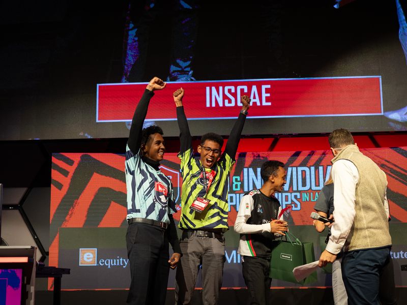 Students from INSCAE celebrating on stage with their arms raised at the MECC championships.